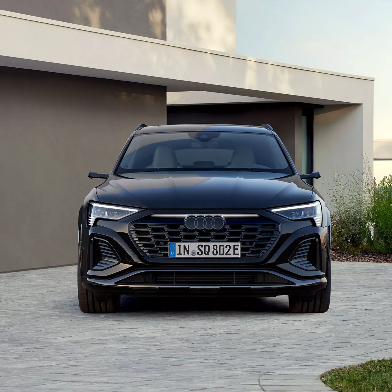 A black Audi vehicle parked beside a modern house