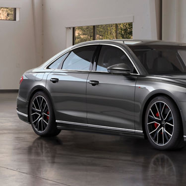 A grey sedan with sporty rims parked in a modern garage.