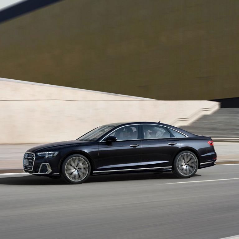 A black sedan driving on a road with motion blur.