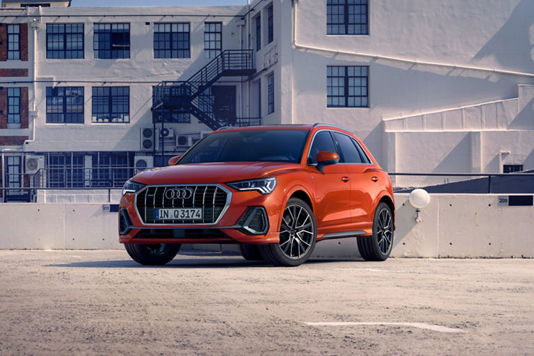 Audi Q3 parked on rooftop space with residential buildings in the background.