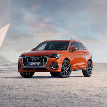 Front angled view of Audi Q3 with steps and building blocks in the background.