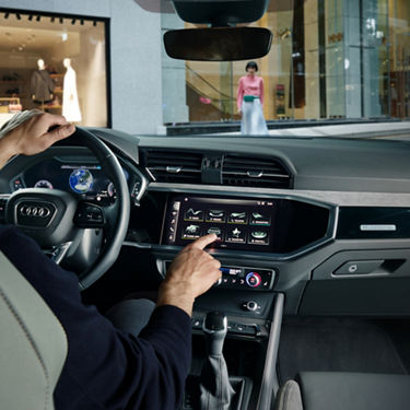 Driver in front seat using touchscreen in Audi Q3.