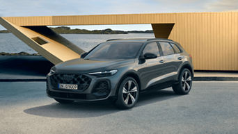 A grey SUV parked near a modern building with a scenic coastal background.