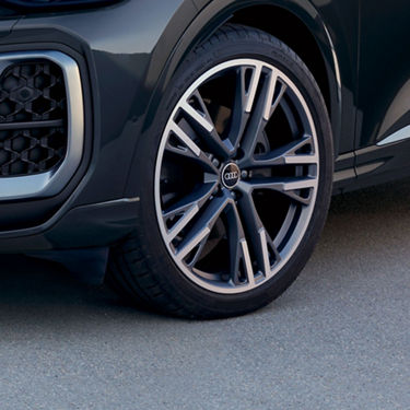 Close-up of a car wheel with the Audi logo on the hubcap.