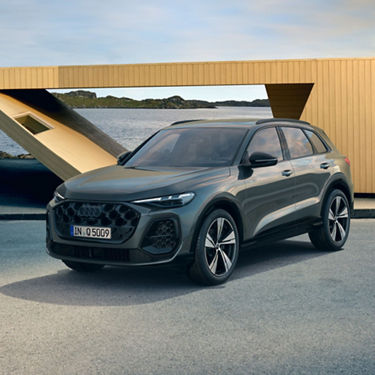 A grey SUV parked near a coastal area with an architectural structure in the background.