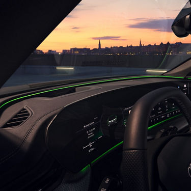 Interior view of a car's dashboard at dusk with city skyline in background.