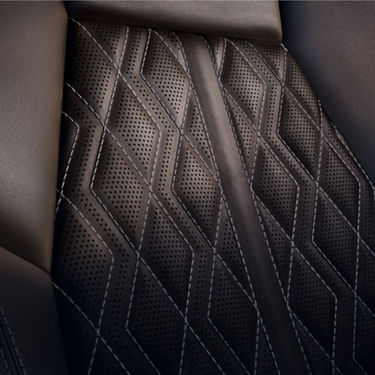 Car seat with black perforated leather and white stitching detail.