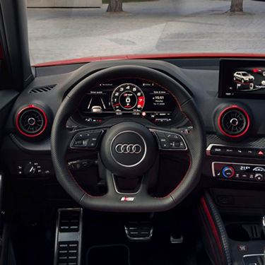 Interior view of an Audi car's steering wheel and dashboard with digital displays.