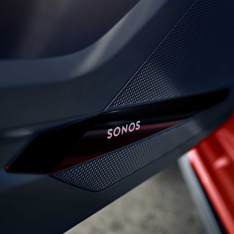 Close-up of a car speaker grille with the logo "SONOS" on a luxury car interior.