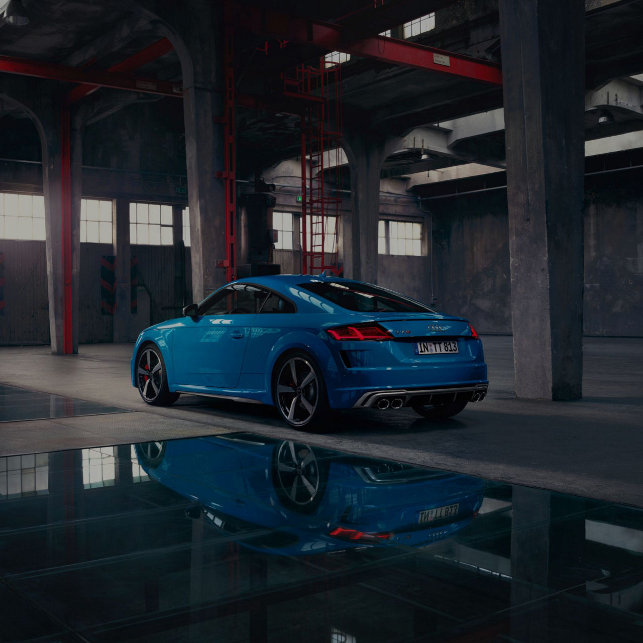 Blue Audi TTS Coupé parked in a concrete spacious building.