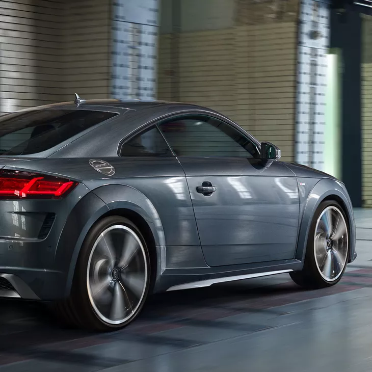 Angled side view of a grey speeding Audi TT in a building.