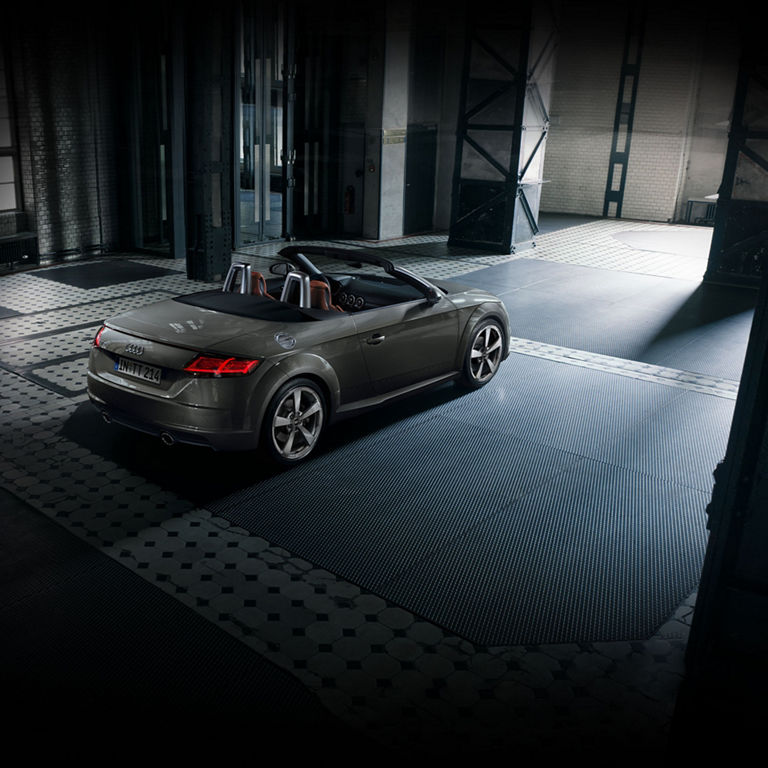 Dark grey soft-top Audi TT Roadster parked in a modern garage.