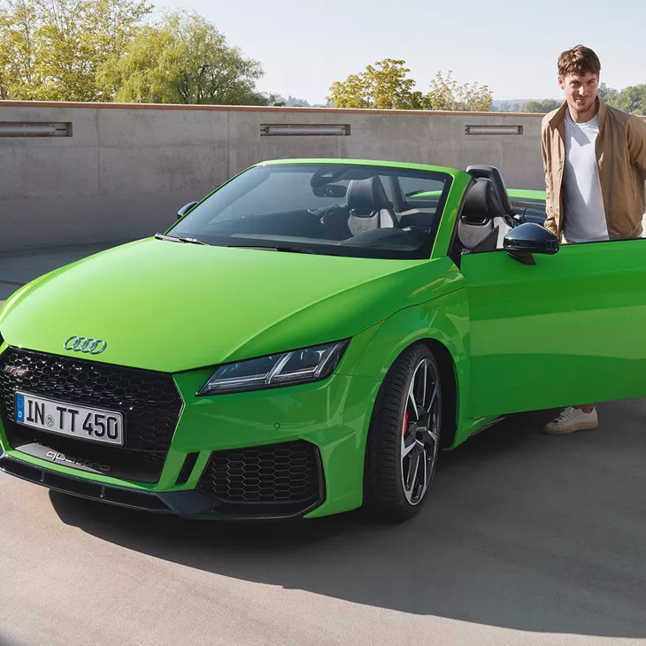 Man entering a green open top Audi TT RS Roadster.