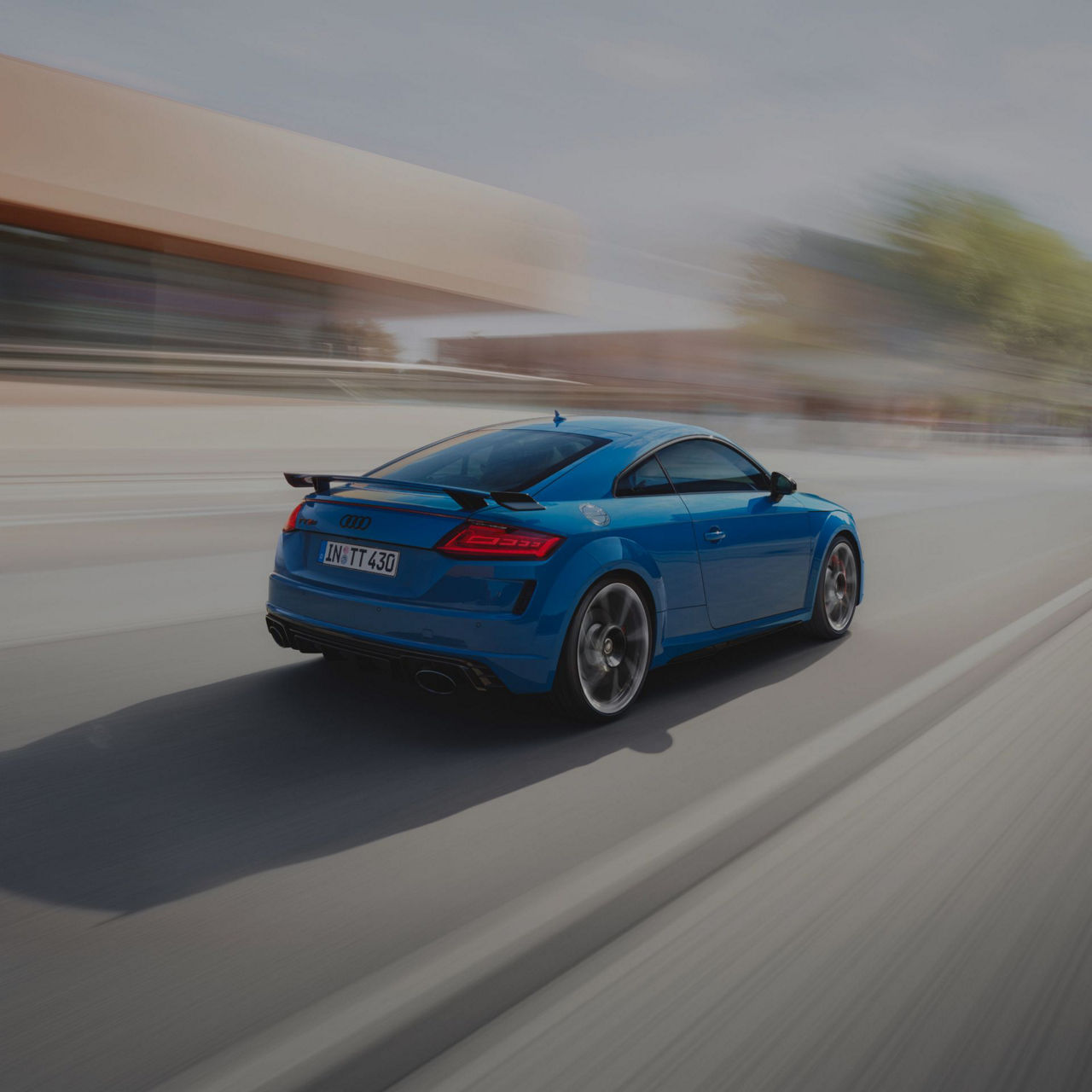 Blue Audi TT RS Roadster moving at speed with a blurred background.