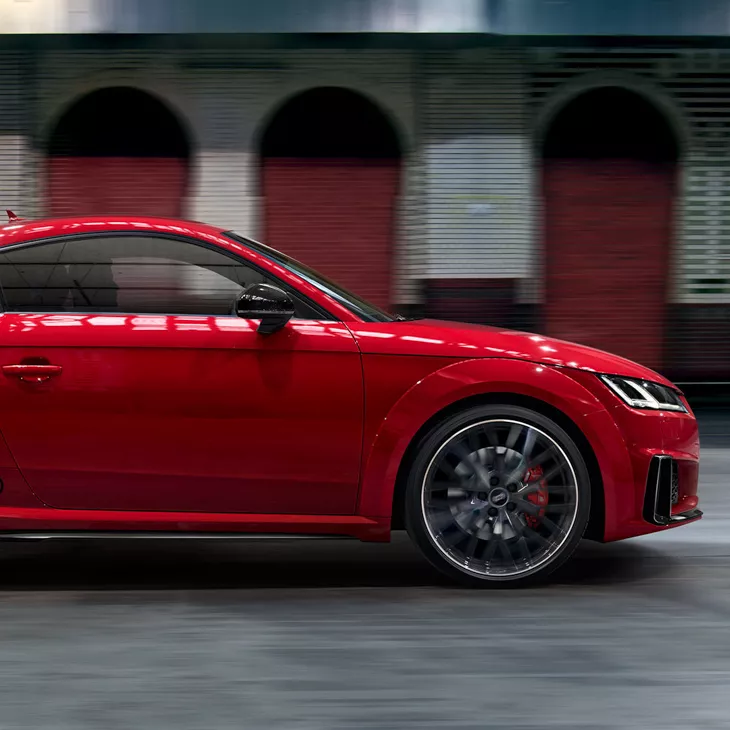 Side view of Red Audi TT with blurred background.