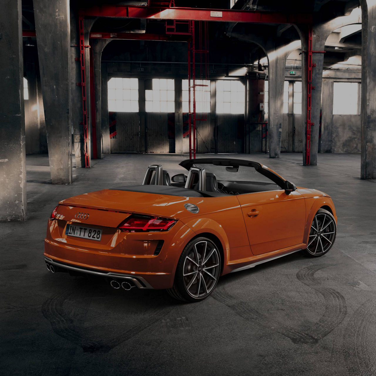 Orange Audi convertible parked in an industrial warehouse setting.