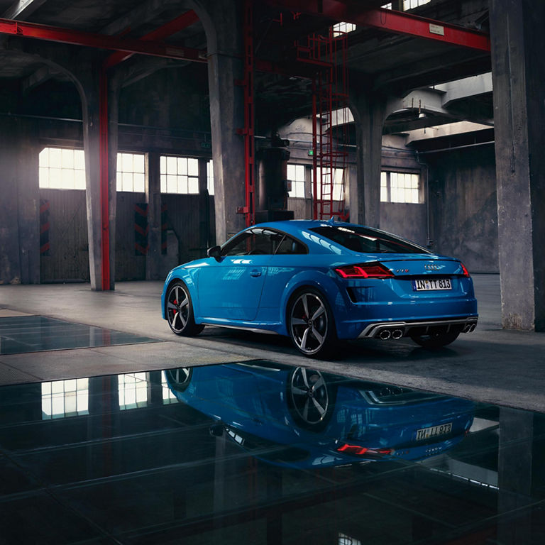 Rear end view of blue Audi TTS Coupe park in garage.