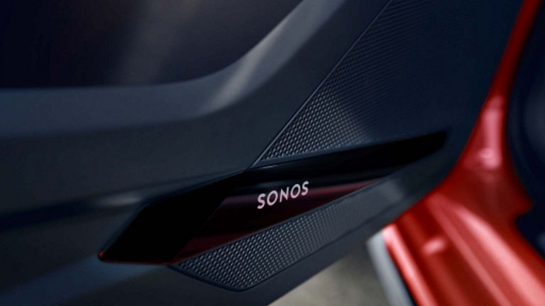 Close-up of an Audi car speaker branded "SONOS" integrated into a door panel with a red exterior visible.