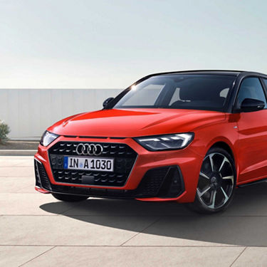 Red Audi A1 Sportback car parked outdoors with clear sky in the background.