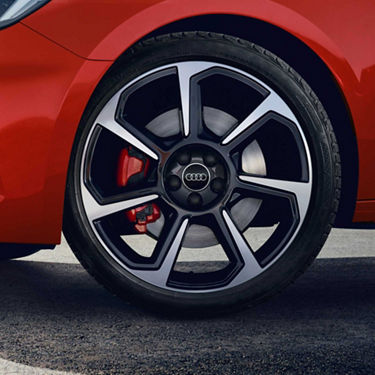 Close-up of a Audi car's alloy wheel with logo and red brake caliper.