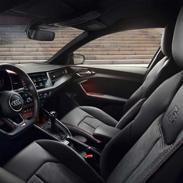 Interior of an Audi A1 Sportback car showing steering wheel, dashboard, and leather seats.
