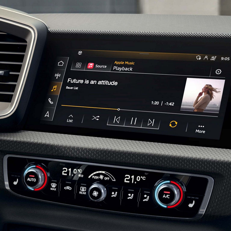 Audi A1 Sportback car infotainment screen displaying music player and climate controls below.