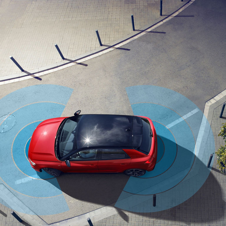 Aerial view of a red Audi A1 Sportback car parked on a patterned pavement showing front and rear sensor.