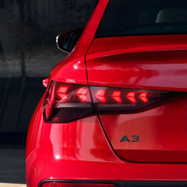 Close-up of a red Audi car's tail light with A3 badge visible.