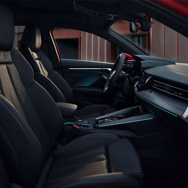 Interior view of a car with black leather seats, dashboard, and touchscreen display.