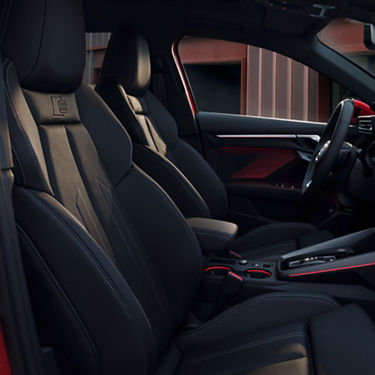 Car interior with black leather seats and red accent stitching.