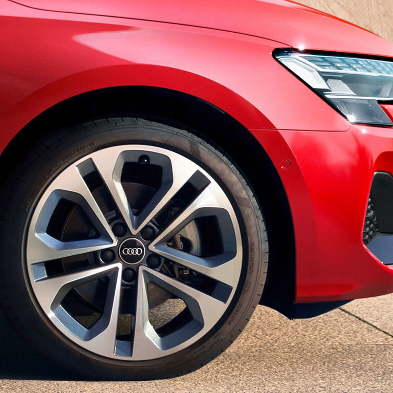 Close-up of a red Audi's front wheel and headlight.