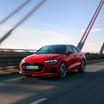 Red Audi A3 Saloon car driving on a bridge with motion blur in the background.