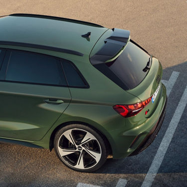 A green car parked diagonally in a parking space, viewed from above and behind.