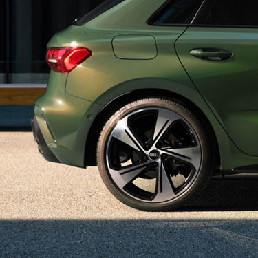 Rear section of a green car with a focus on the alloy wheel.