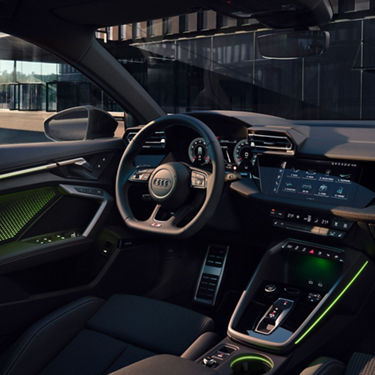 An Audi car interior with steering wheel, dashboard displays, and center console.