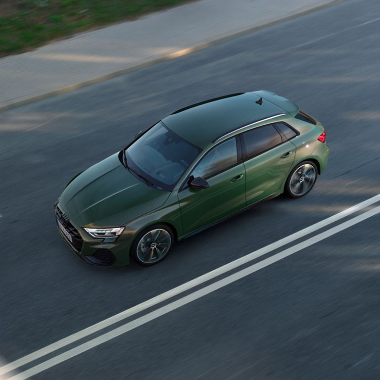 Aerial view of a green Audi car driving on a road.