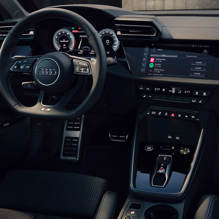 Interior of an Audi car showing the steering wheel, dashboard, and center console.