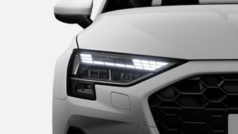 Close-up of a car's front corner, showcasing LED headlights and hexagonal grille design.