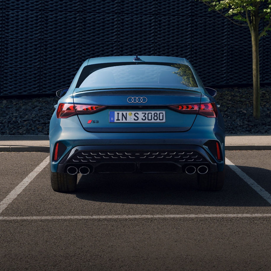 Rear view of a blue Audi car parked with visible license plate and dual exhausts