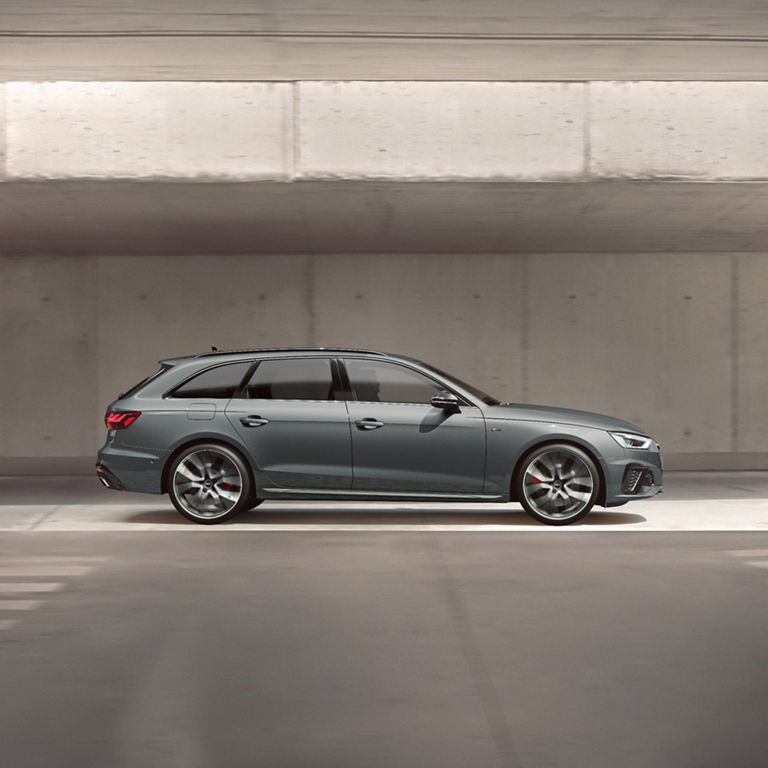 A modern grey car parked in a concrete parking garage.