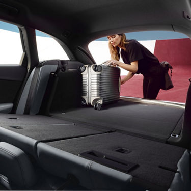 Person loading a silver suitcase into the trunk of a car.