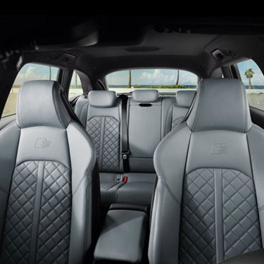 Car interior with quilted leather seats and emblem on headrests.