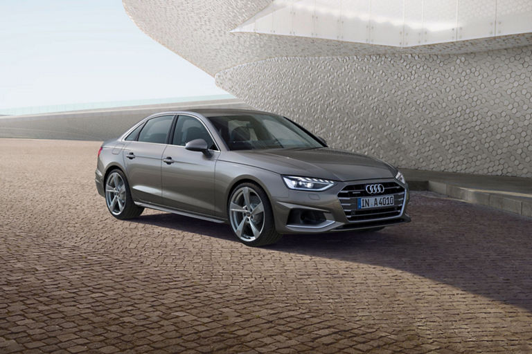 A silver Audi A4 Saloon parked outside a modern building with hexagonal facade patterns.