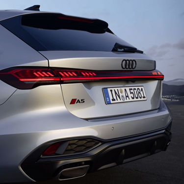 Rear view of a silver Audi A5 Avant car with distinctive taillights and a spoiler, at dusk.