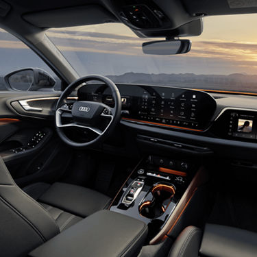 Interior of an Audi car with leather seats and modern dashboard at sunset.