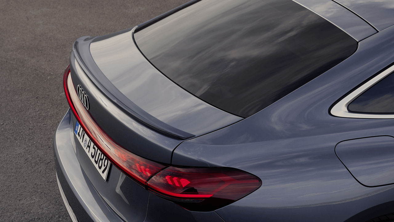 Close-up of a grey car's rear with distinctive taillights and logo, showcasing a sleek design.