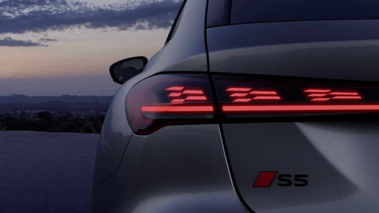 Rear view of a car with illuminated LED taillights at dusk.