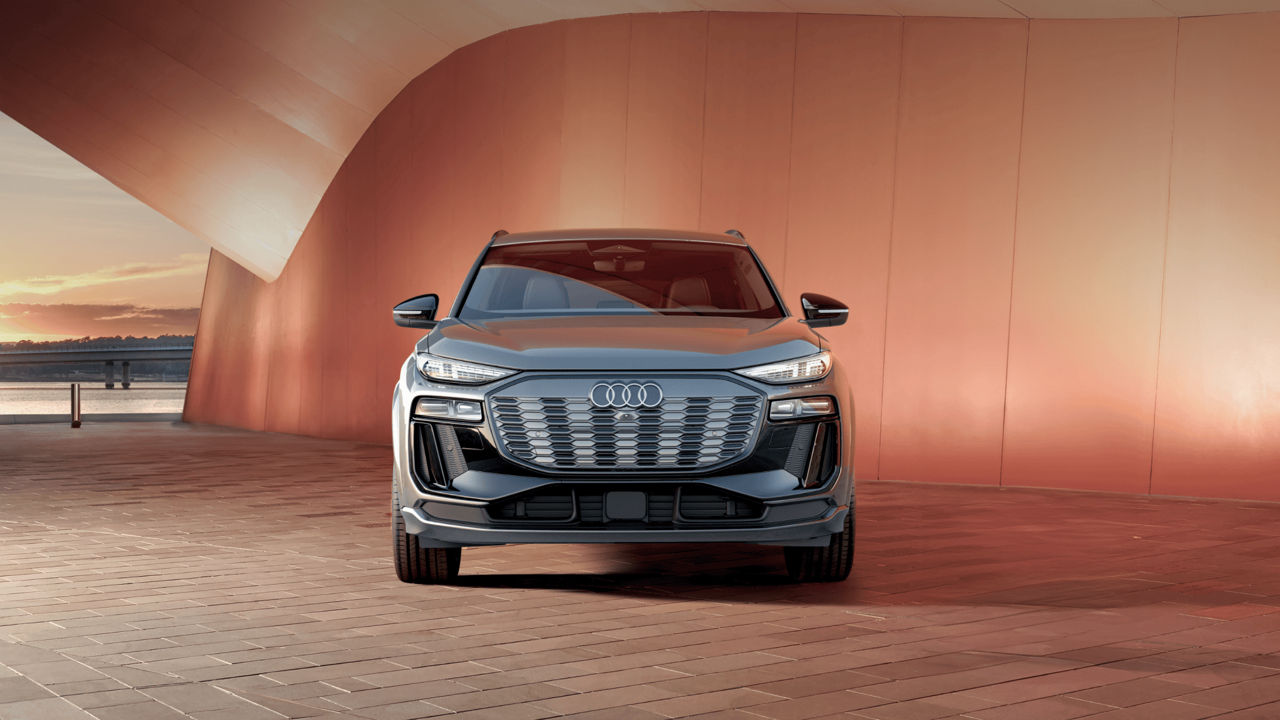 Audi SUV parked in front of an orange architectural structure at dusk.