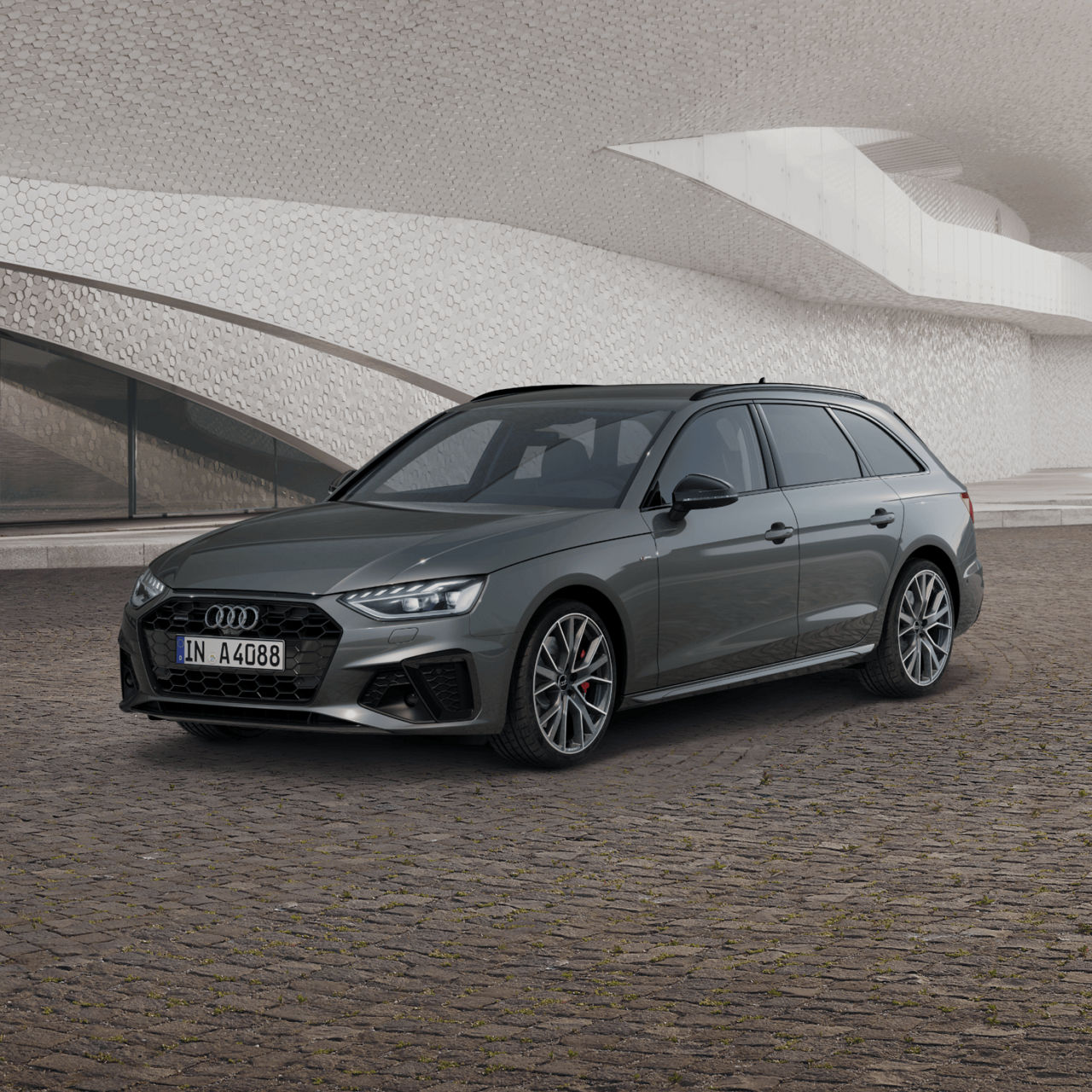 Grey Audi A4 Avant parked in front of a modern, textured building.