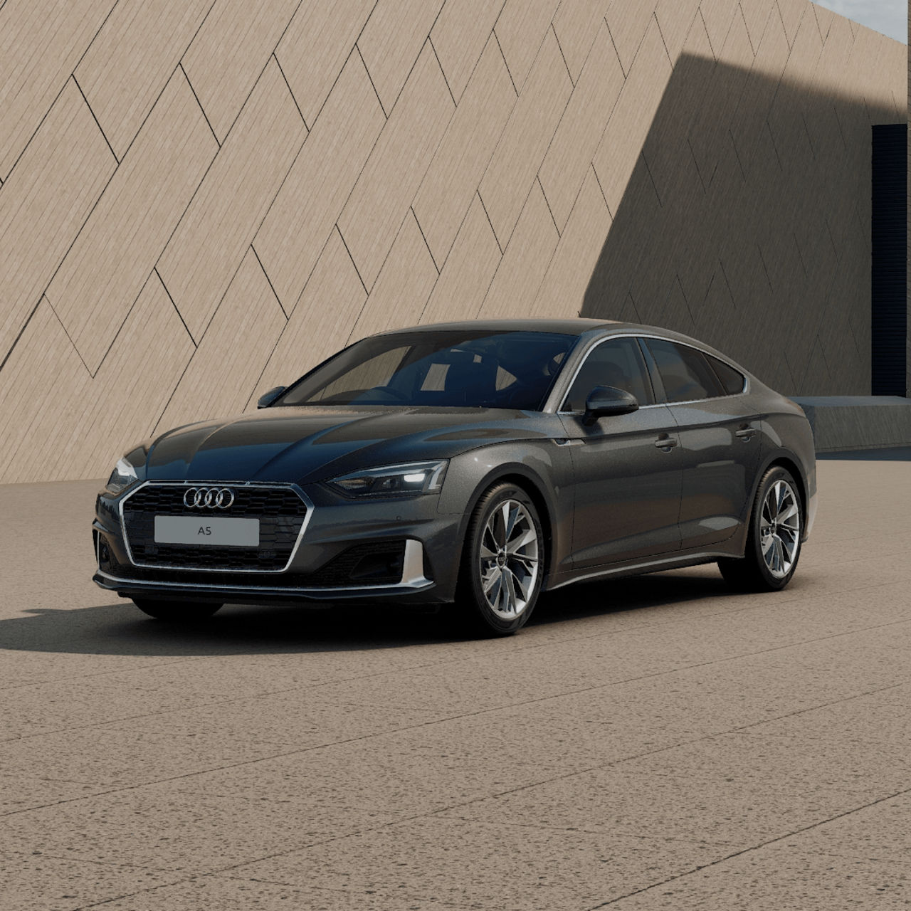 A grey Audi A5 Sportback parked in front of a modern building with a textured facade.